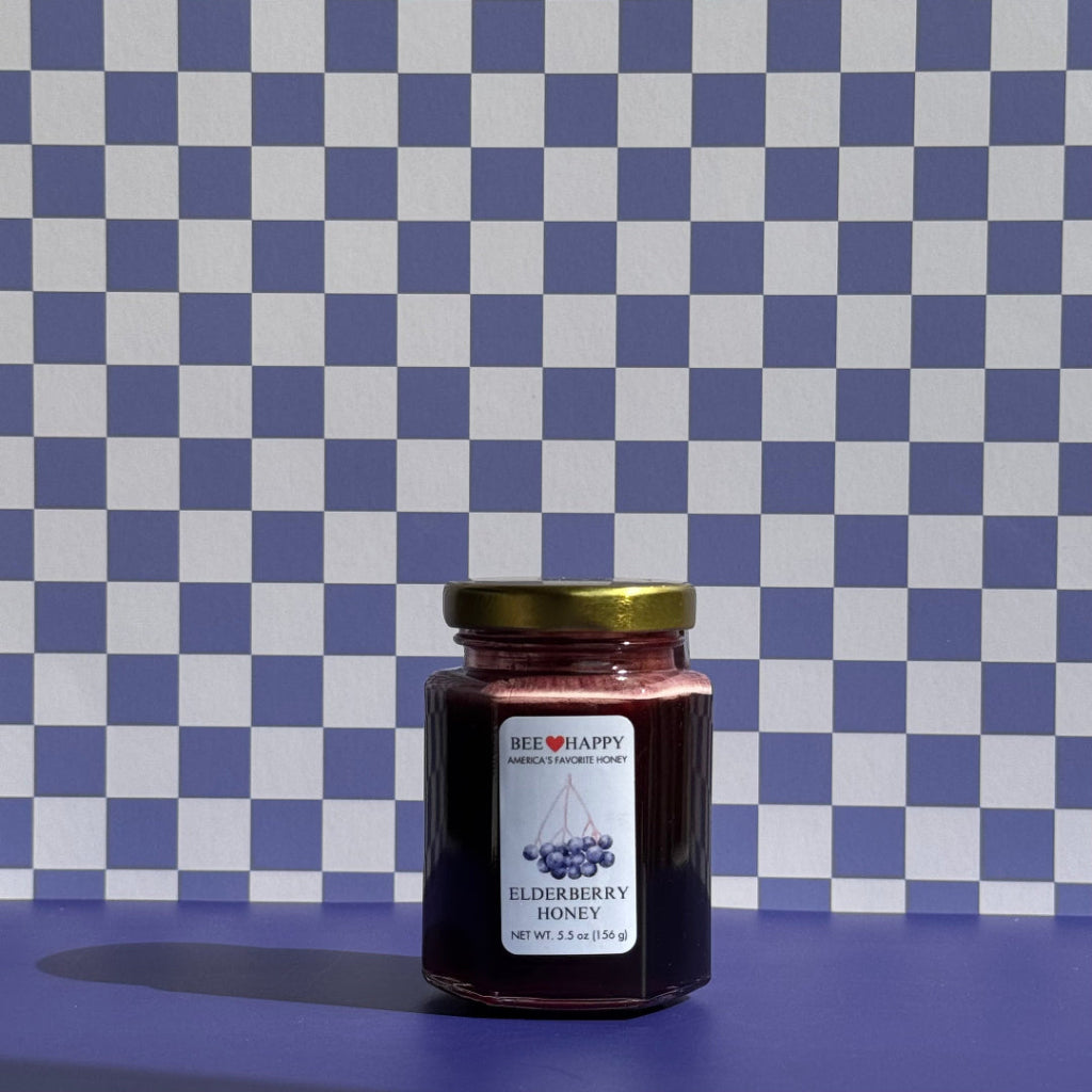 Jar of Elderberry Honey with a gold lid on a blue and white checkered background