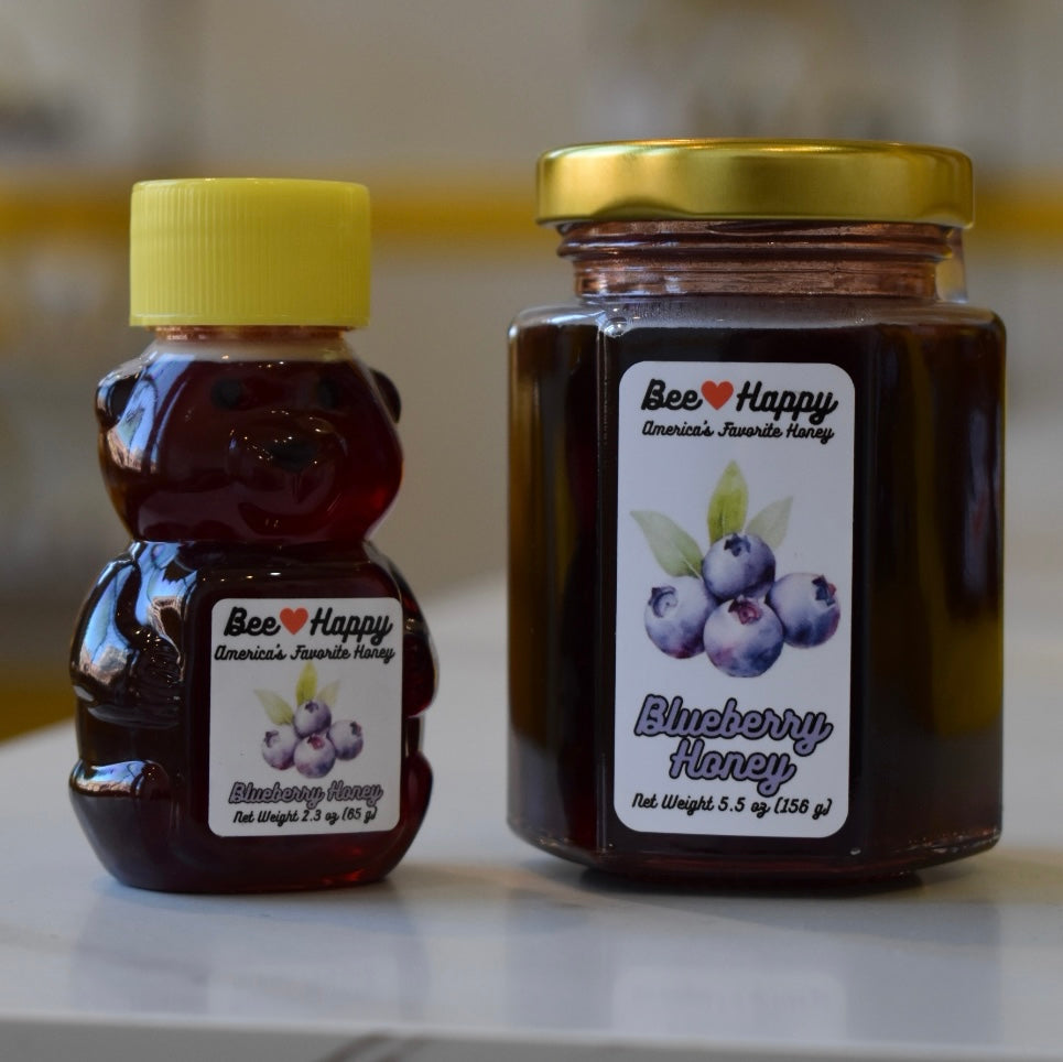 2.3 oz bear bottle and 5.5 oz jar of Blueberry Honey on a white glossy surface with a blurry background