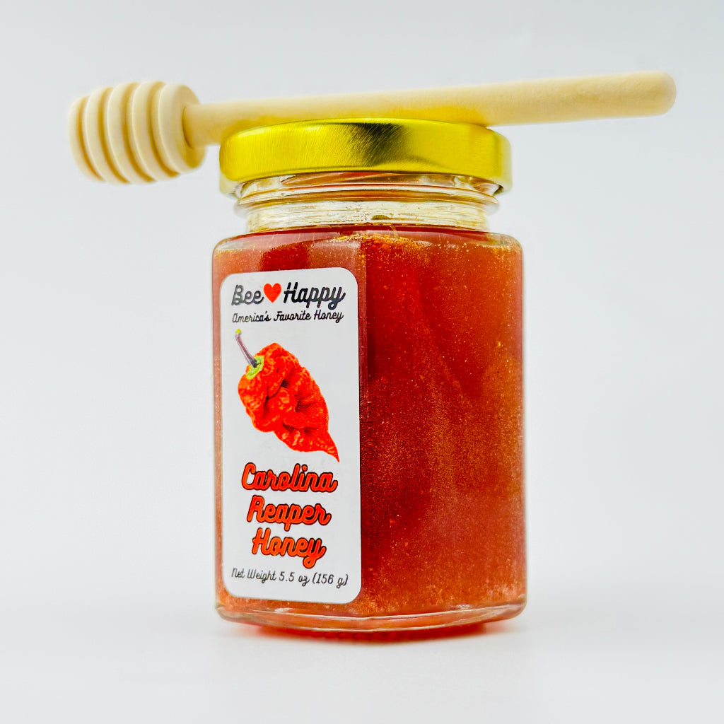 5.5 oz jar of Carolina Reaper Honey with a honey dipper on top on a white background