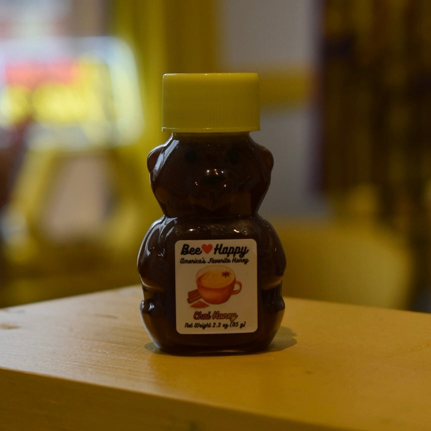 2.3 oz bear bottle of Chai Honey on a wooden surface with a blurred background.