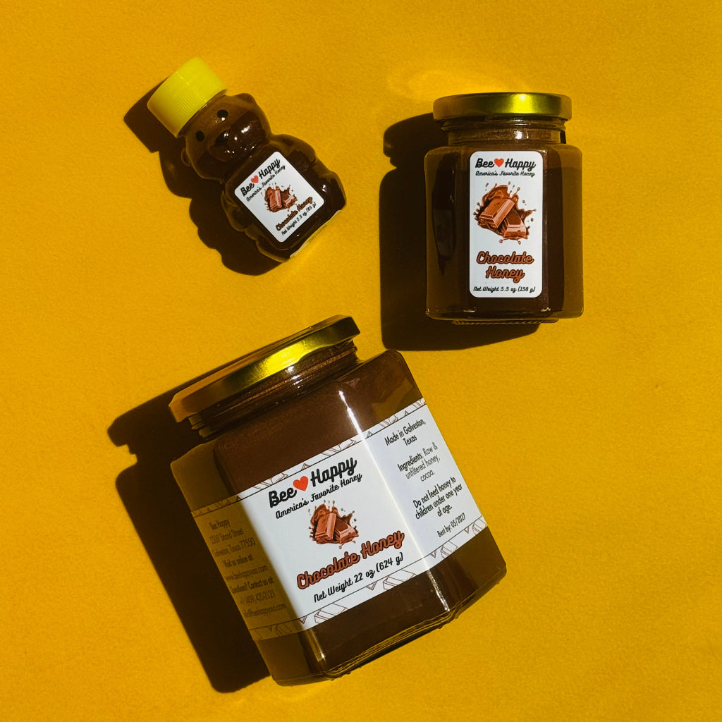 2.3 oz bear bottle, 5.5 oz jar and 22 oz jar of Chocolate Honey with a laying on an orange surface