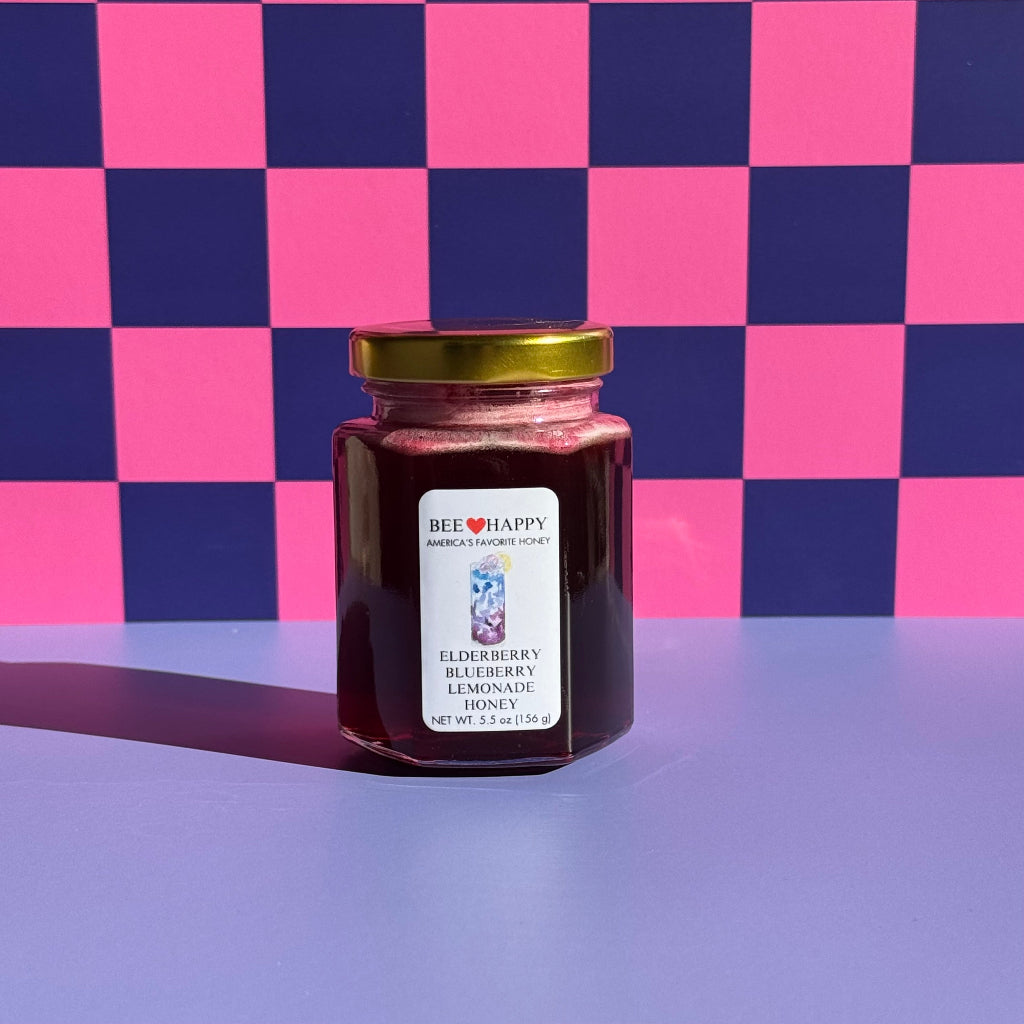 5.5 oz jar of Bee Happy Elderberry Blueberry Lemonade on a pink and blue checkered background