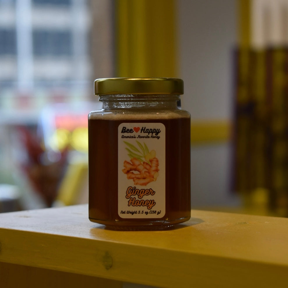 5.5 oz jar of Ginger Honey on a wooden surface with a blurred background.