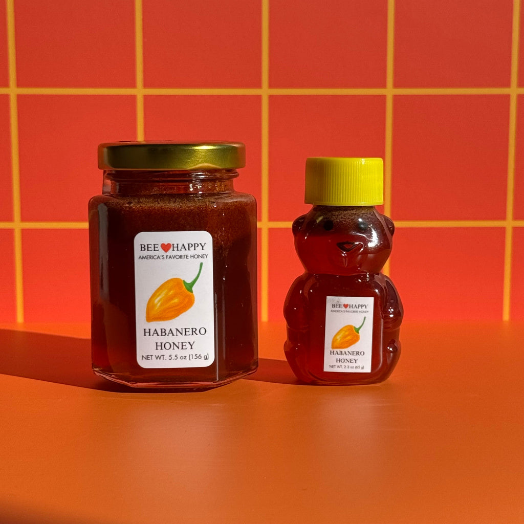 5.5 oz jar and 2.3 oz bear bottle of Bee Happy Habanero Honey on an orange background
