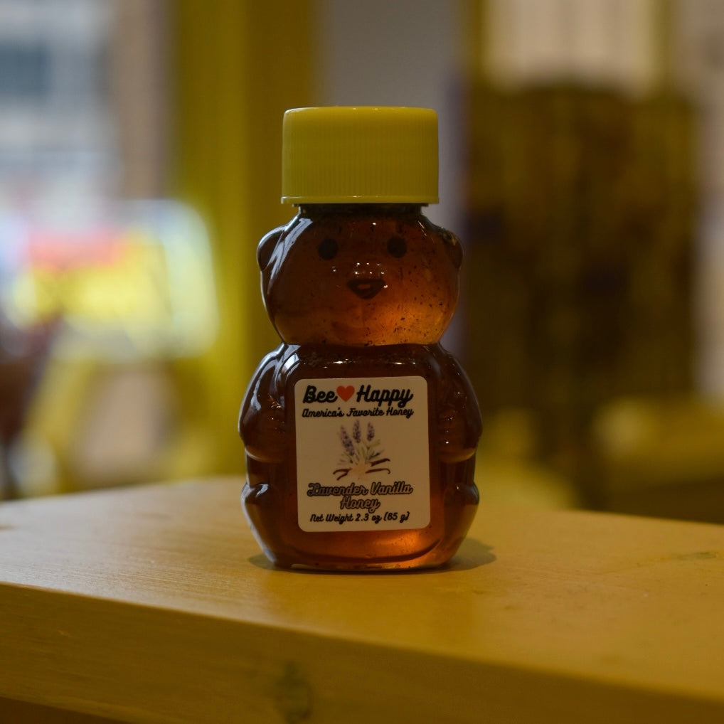 2.3 oz bear bottle of Lavender Vanilla Honey on a wooden surface with a blurred background.