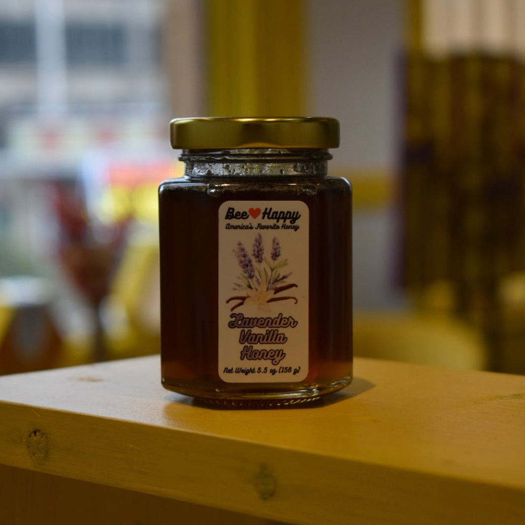 5.5 oz jar of Lavender Vanilla Honey on a wooden surface with a blurred background.
