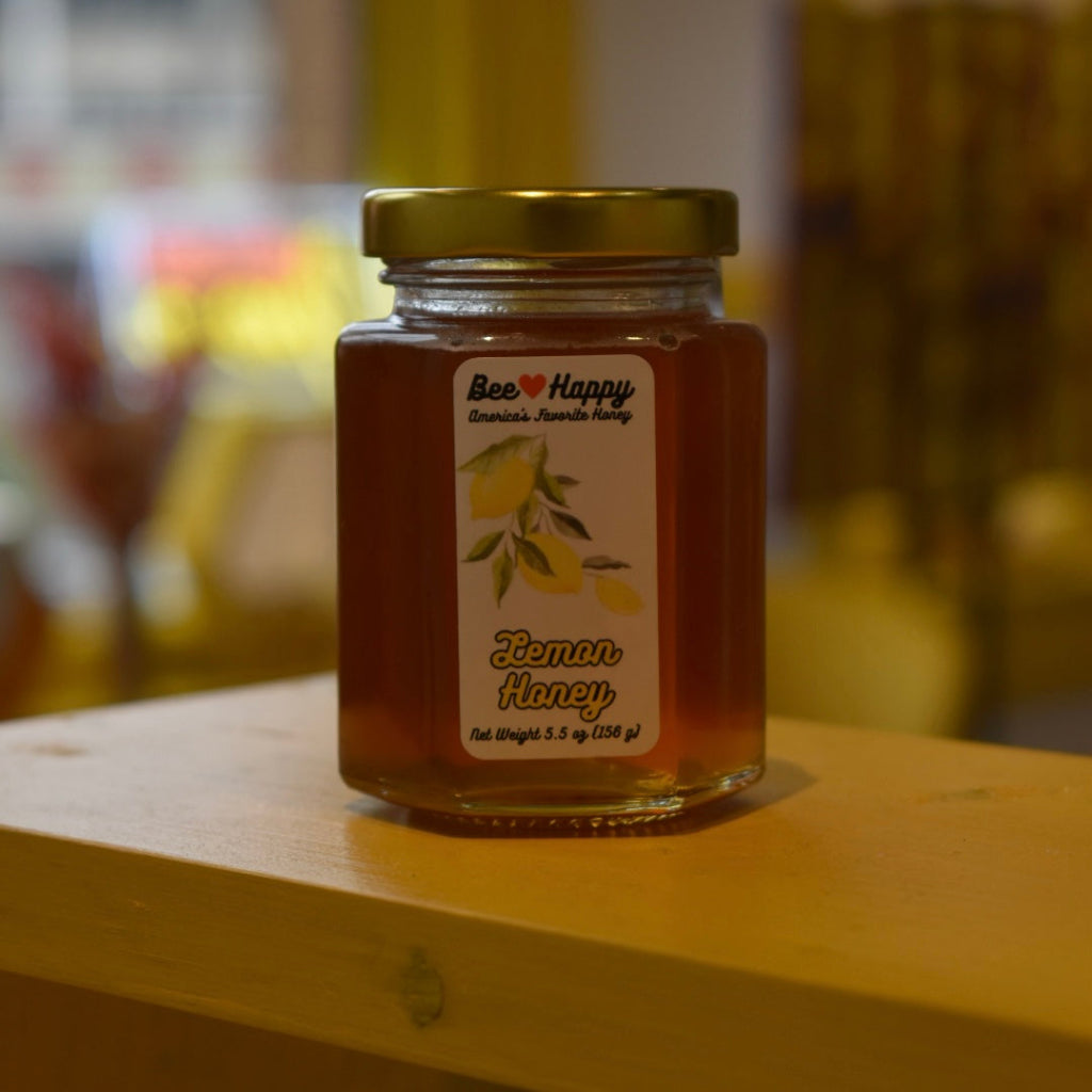 5.5 oz jar of Lemon Honey on a wooden surface with a blurred background.