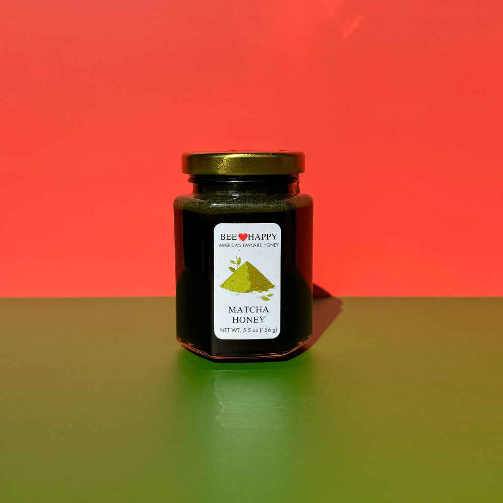 Jar of 5.5 oz Bee Happy Matcha Honey on a red and green background