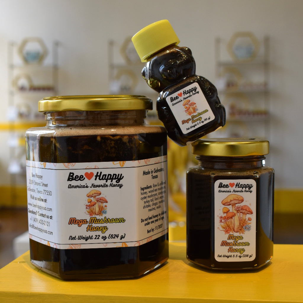 22 oz jar, 5.5 oz jar and 2.3 oz bear bottle of Mega Mushroom Honey on a yellow surface with a blurred background.