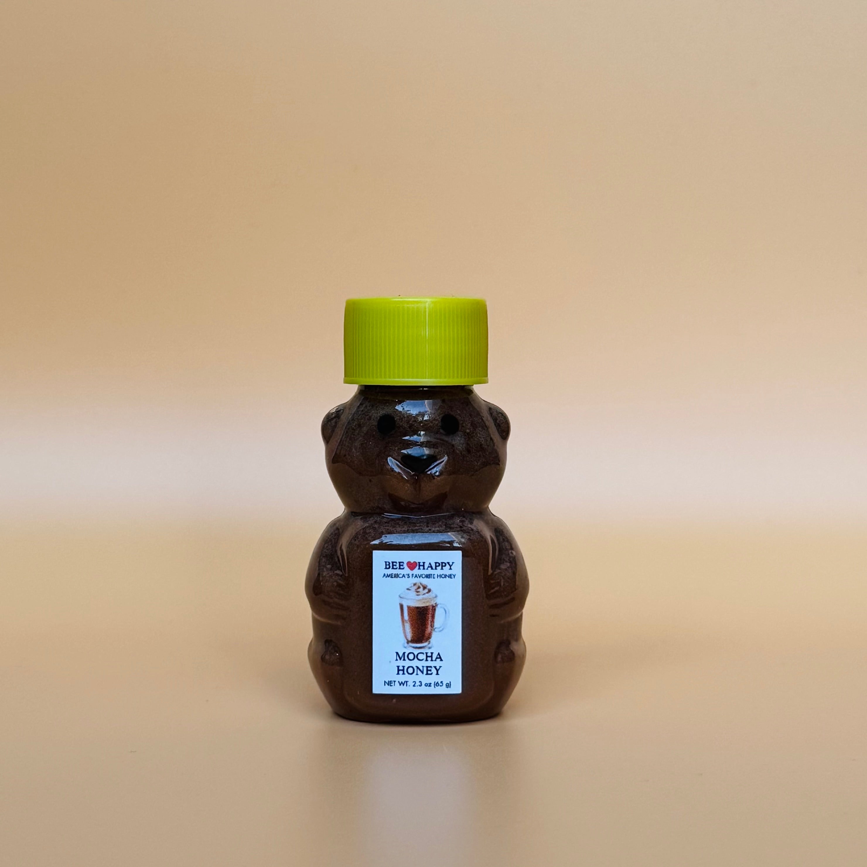2.3 oz bear bottle of Bee Happy Mocha Honey with a beige background.