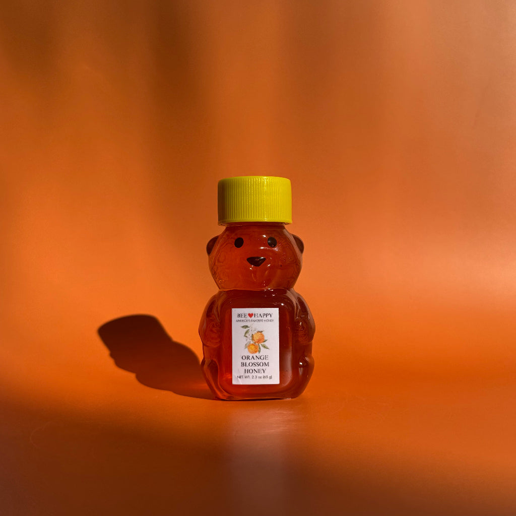 2.3 oz bear bottle of Orange Blossom Honey against an orange background