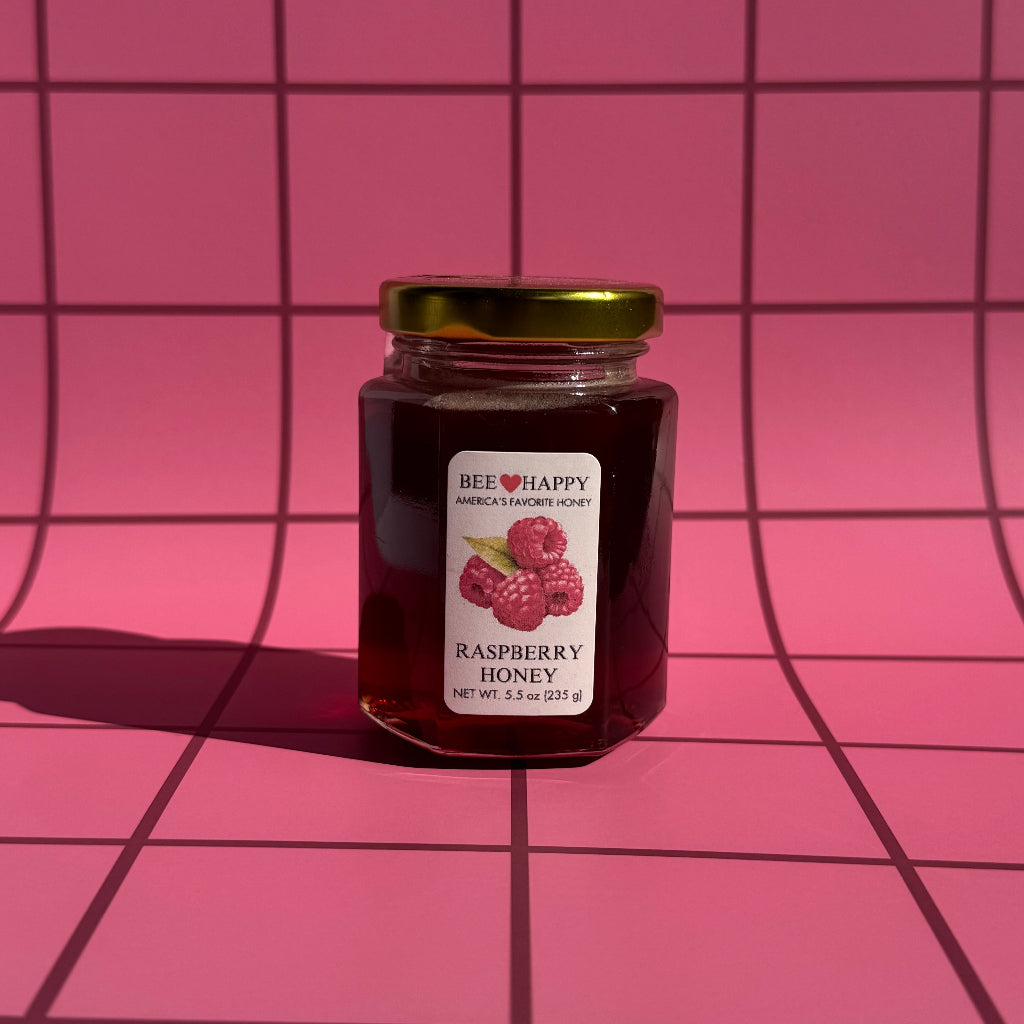 5.5 oz jar of Raspberry Honey on a pink grid background
