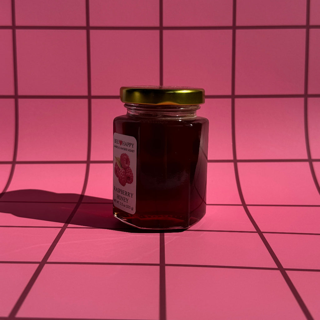 5.5 oz jar of Raspberry Honey on a pink grid background