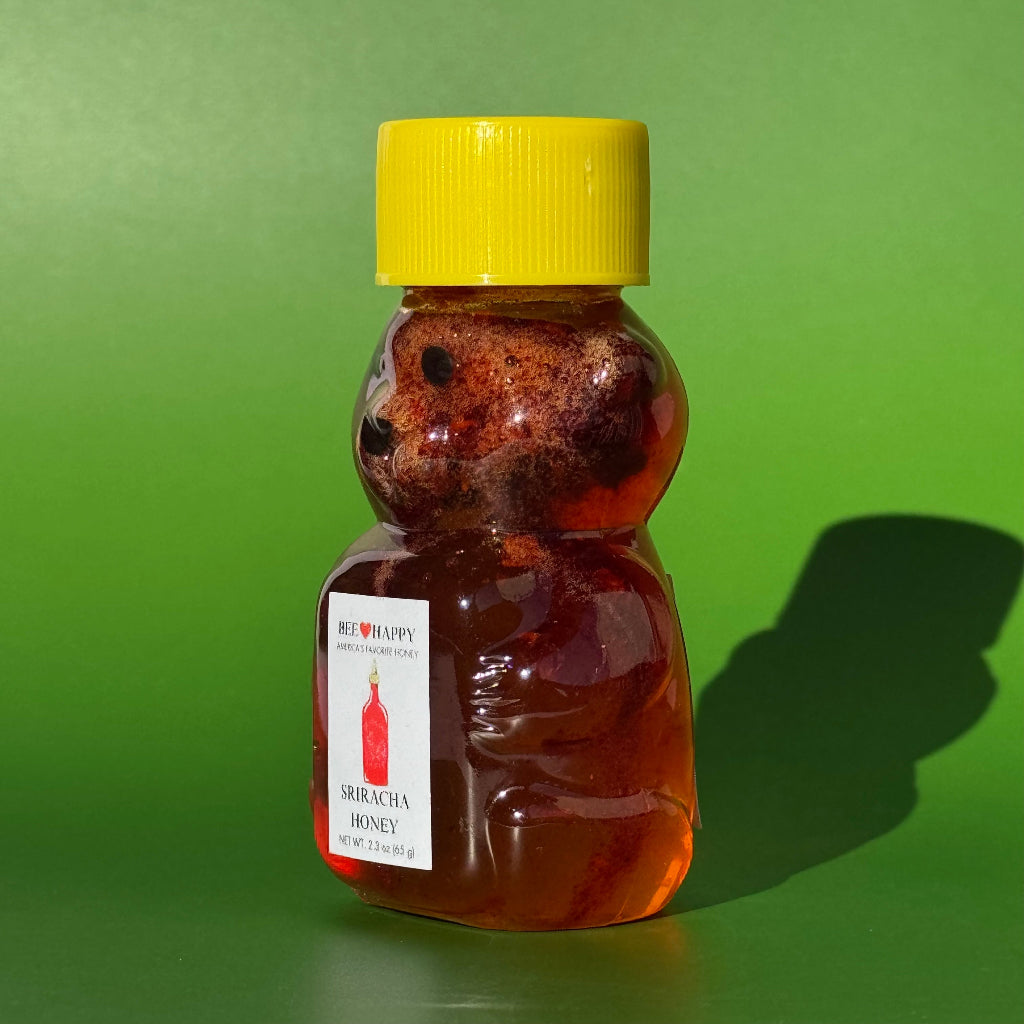 Angled view of 2.3 oz bear bottle of Sriracha Honey with a green background