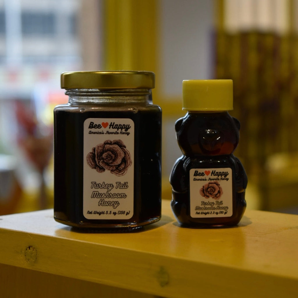 5.5 oz jar and 2.3 oz bear bottle of Turkey Tail Mushroom Honey on a wooden surface with a blurred background.