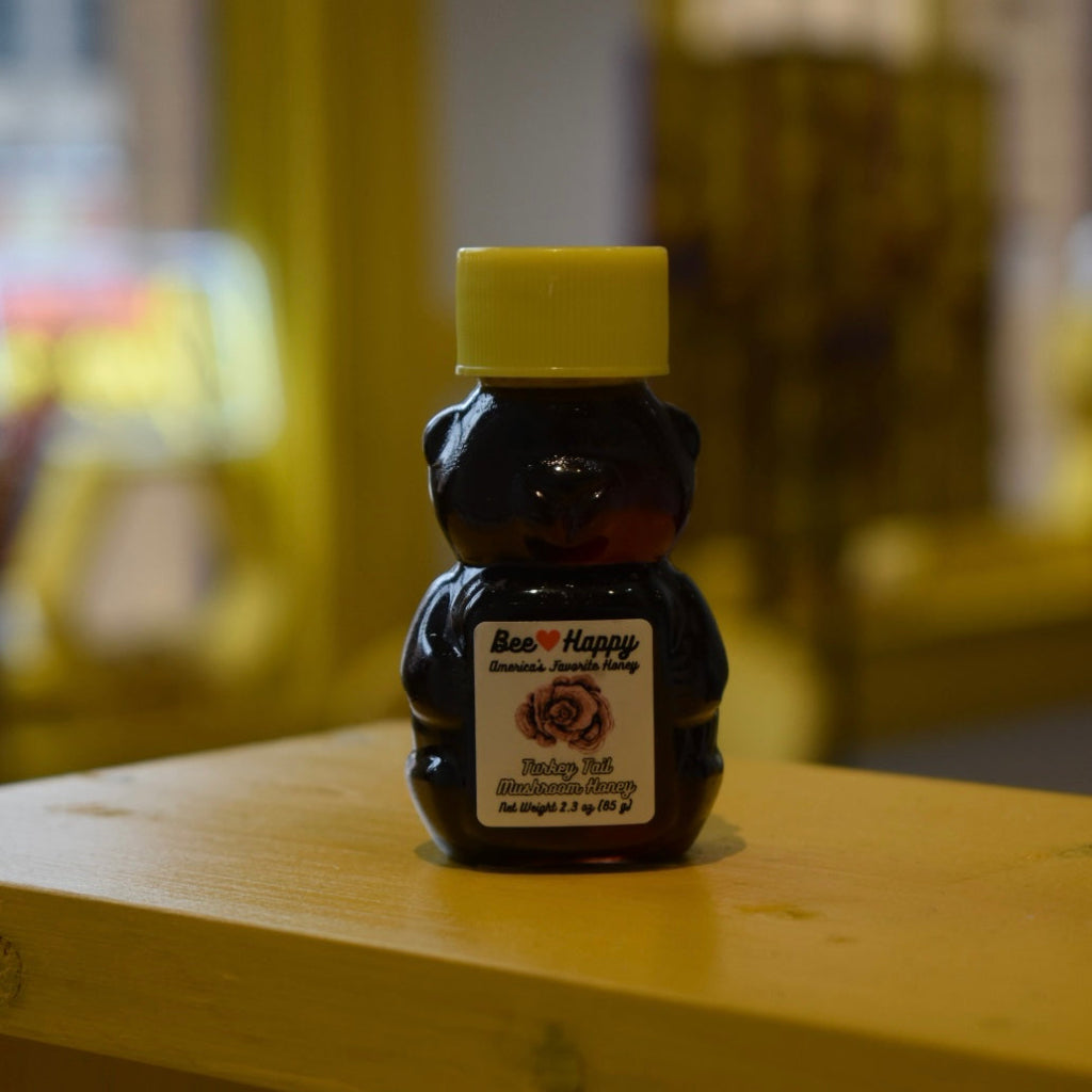 2.3 oz bear bottle of Turkey Tail Mushroom Honey on a wooden surface with a blurred background.