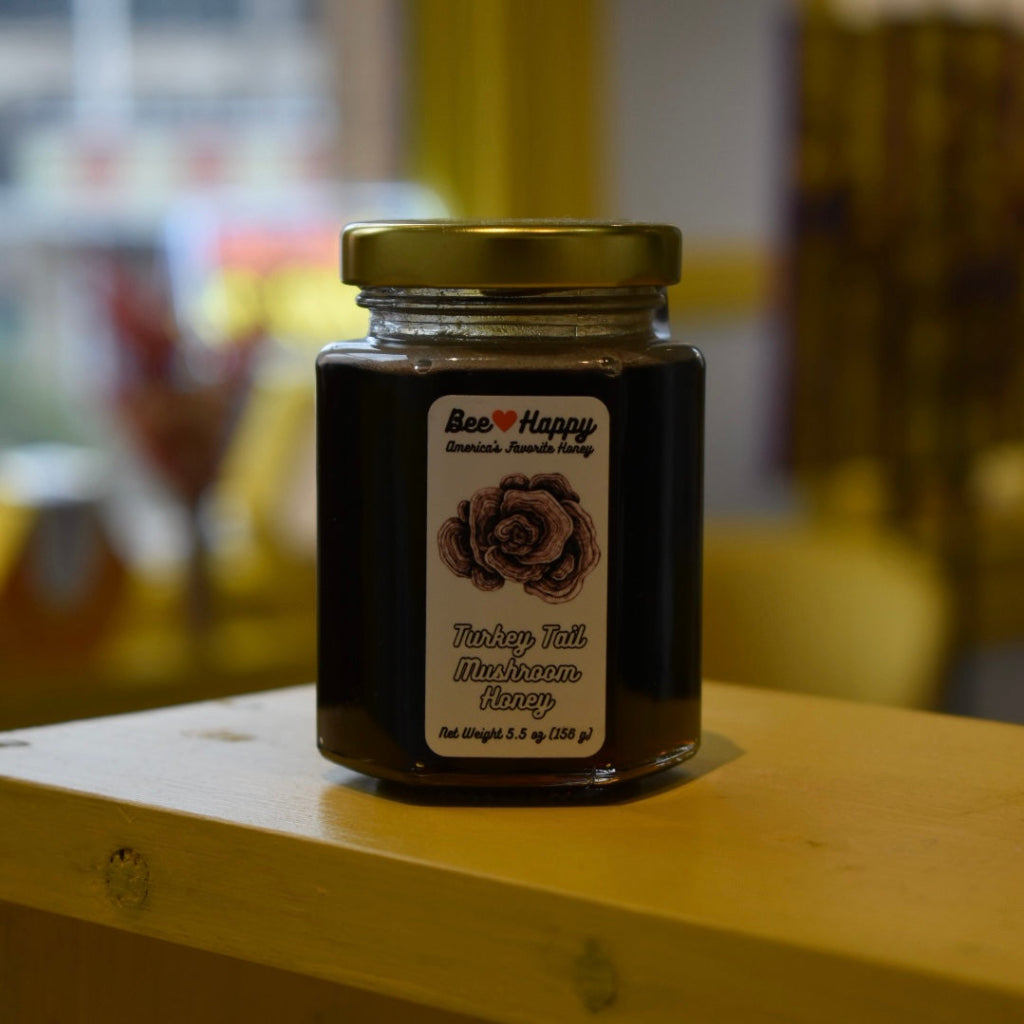 5.5 oz jar of Turkey Tail Mushroom Honey on a wooden surface with a blurred background.