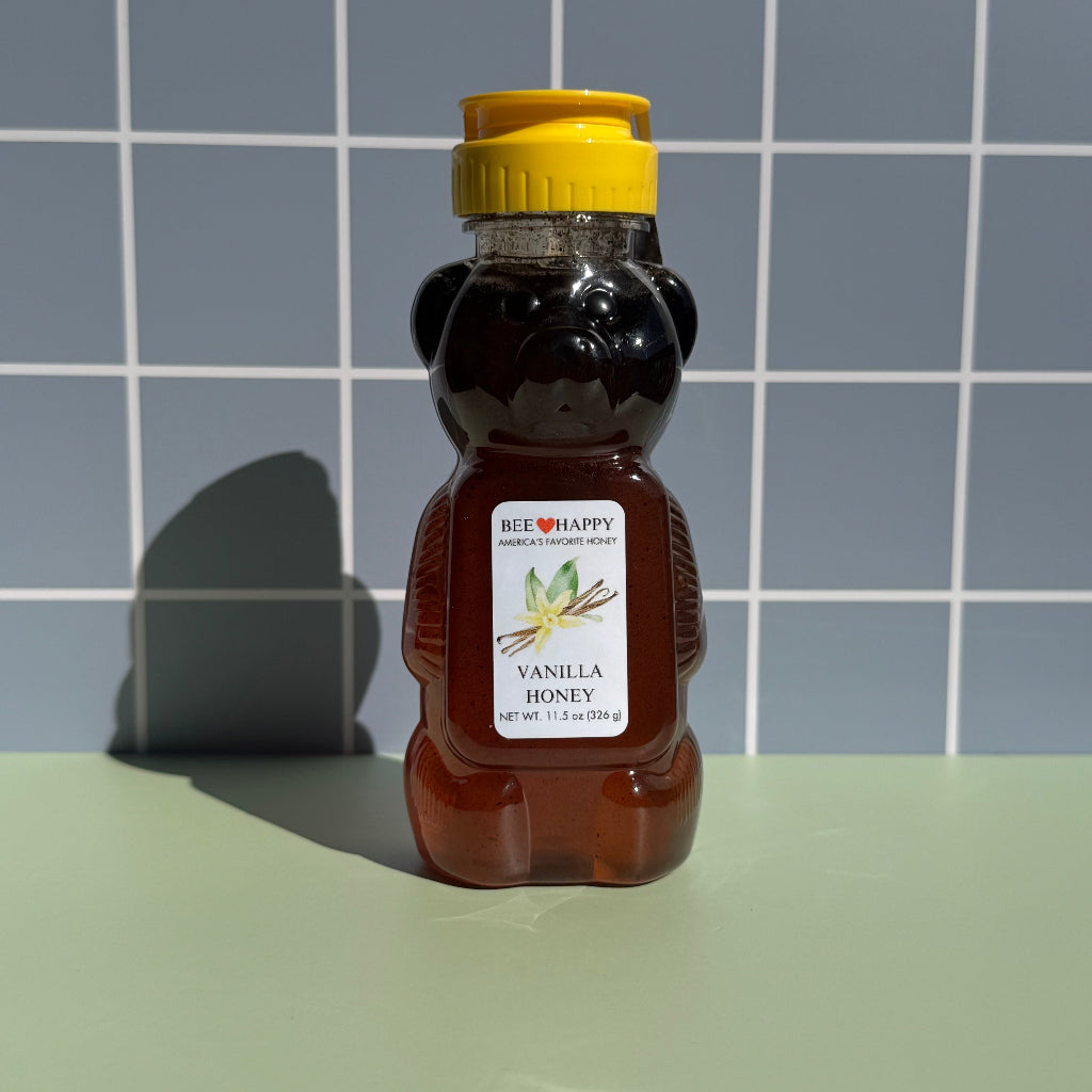 11.5 oz bear bottle of Bee Happy Vanilla Honey on a gray checkered background
