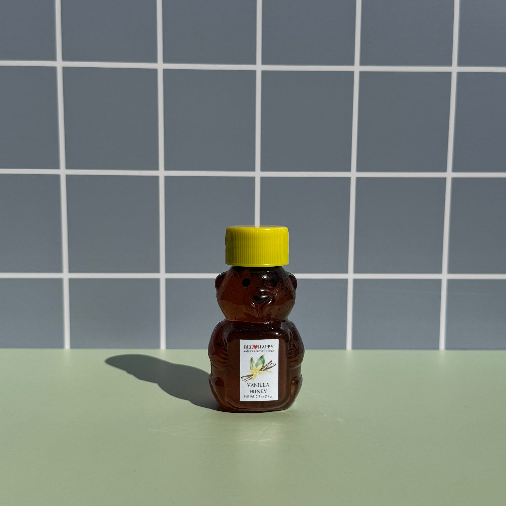 2.3 oz bear bottle of Bee Happy Vanilla Honey on a gray checkered background