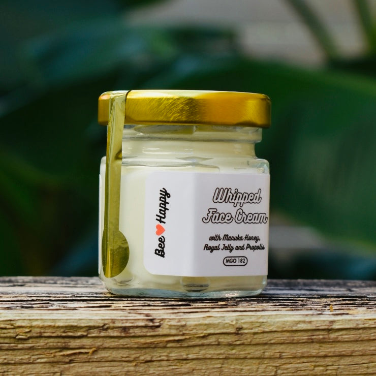 1 oz jar of Whipped Face Cream on a wooden surface with a blurry green background