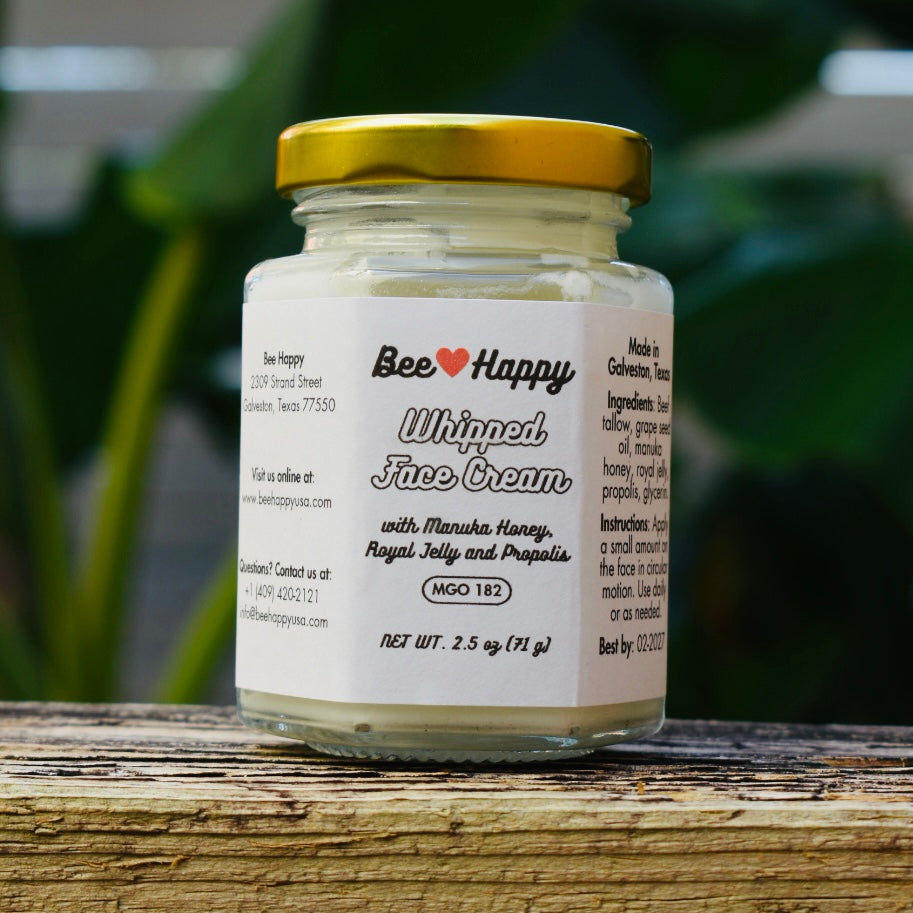 2.5 oz jar of Whipped Face Cream on a wooden surface with a blurry green background