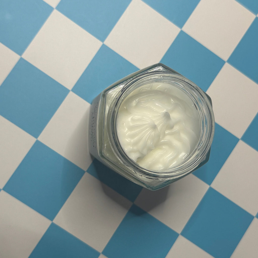Open jar of Bee Happy 4 oz Whipped Face Cream on a blue and white checkered background