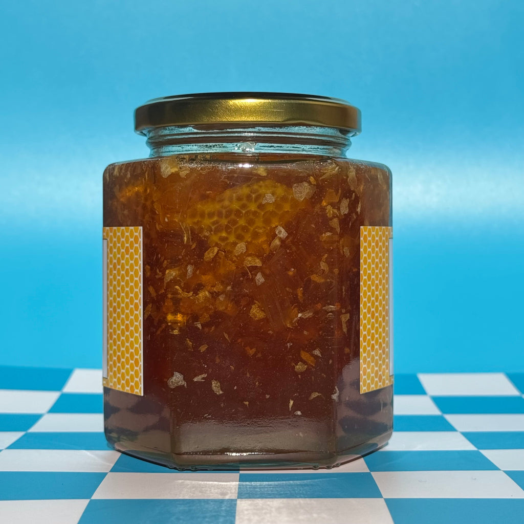22 oz jar of Bee Happy Wild Honey with Comb on a blue and white checkered background